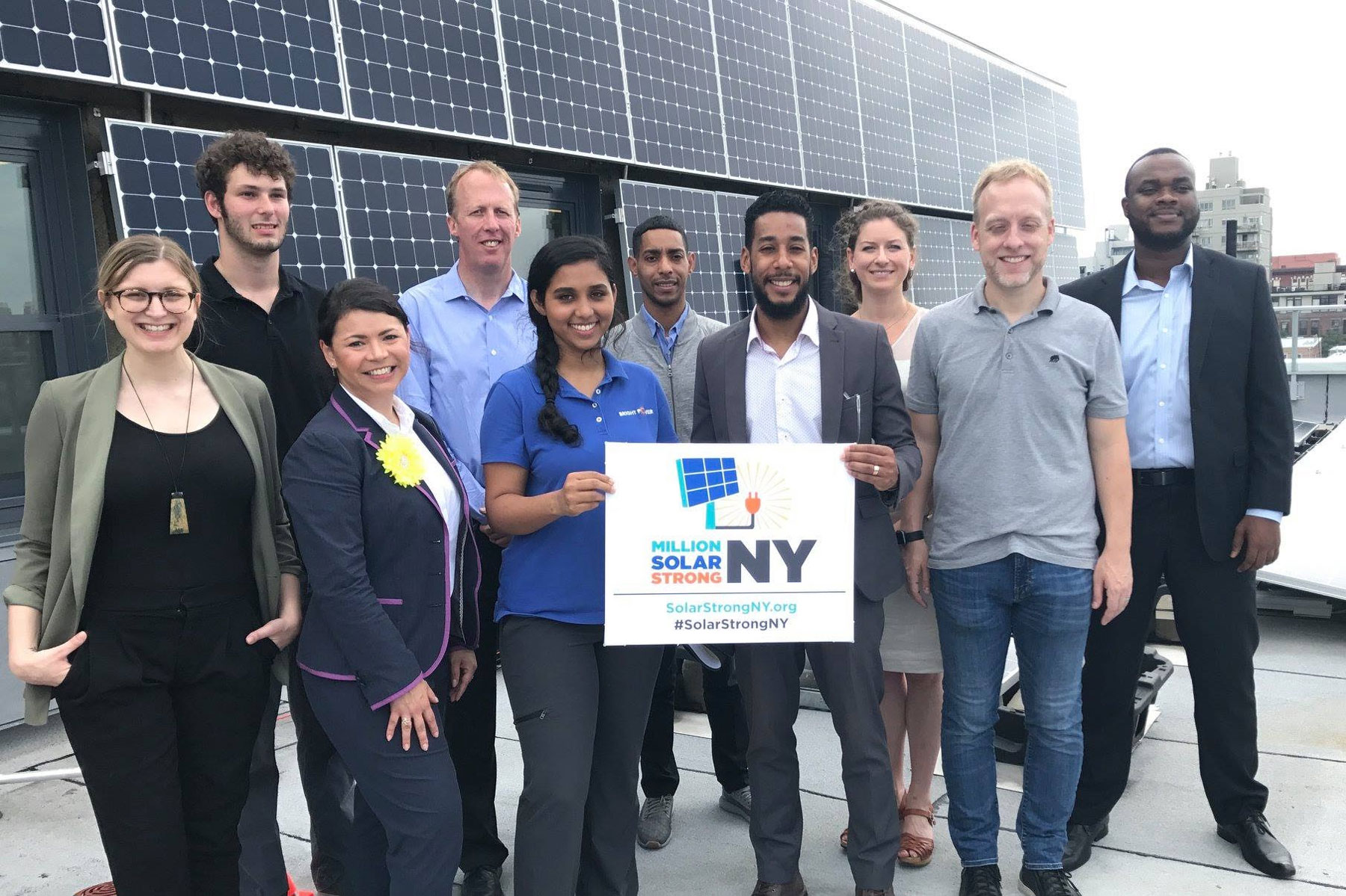 Million Solar Strong NY poses in front of solar panel